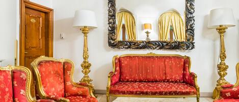 Una habitación con un sofá rojo, sillones a juego, una mesita de centro y dos lámparas de pie.