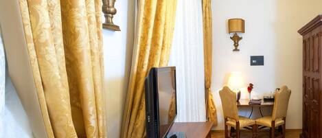 A hotel room with a wooden desk, two chairs, a computer, and a lamp.