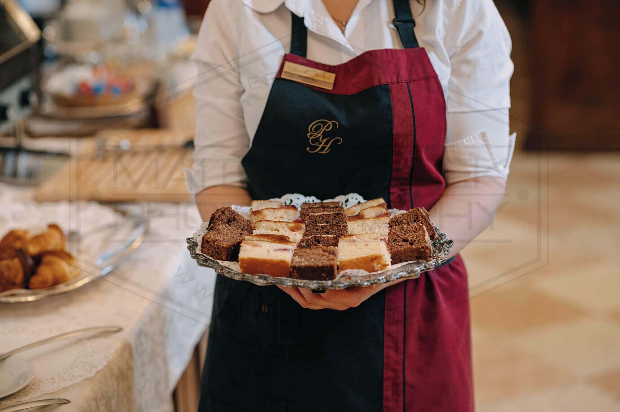 Une personne tenant un plateau sur lequel se trouvent différents types de gâteaux.