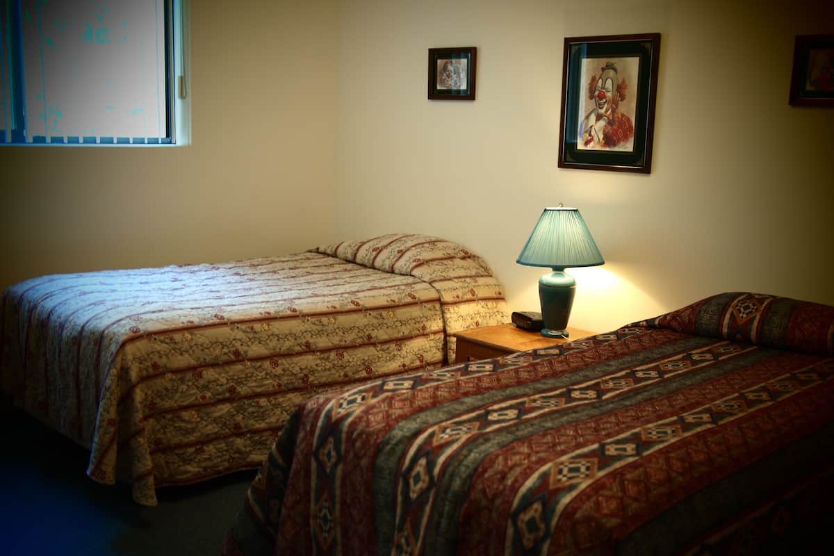 A bedroom with two beds, a nightstand with a lamp, and a framed picture on the wall.