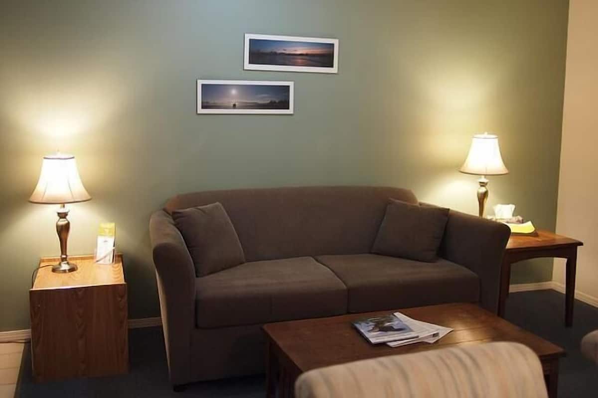 A living room with a sofa, two side tables with lamps, and two framed pictures on the wall.