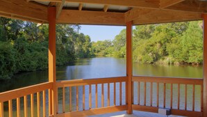 Una terraza de madera con vistas a un río y follaje circundante.