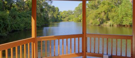 Una terraza de madera con vistas a un río y follaje circundante.
