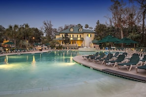 A pool area with lounge chairs and umbrellas, a fountain, and a building with a green roof in the background. - Waterside by Spinnaker Resorts (Hilton Head Island)
