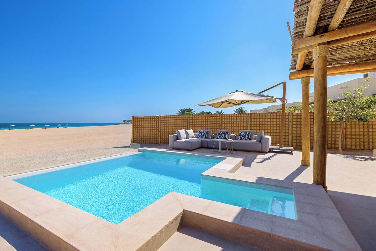 Ein Poolbereich mit Sitzgelegenheiten und Blick auf den Strand.