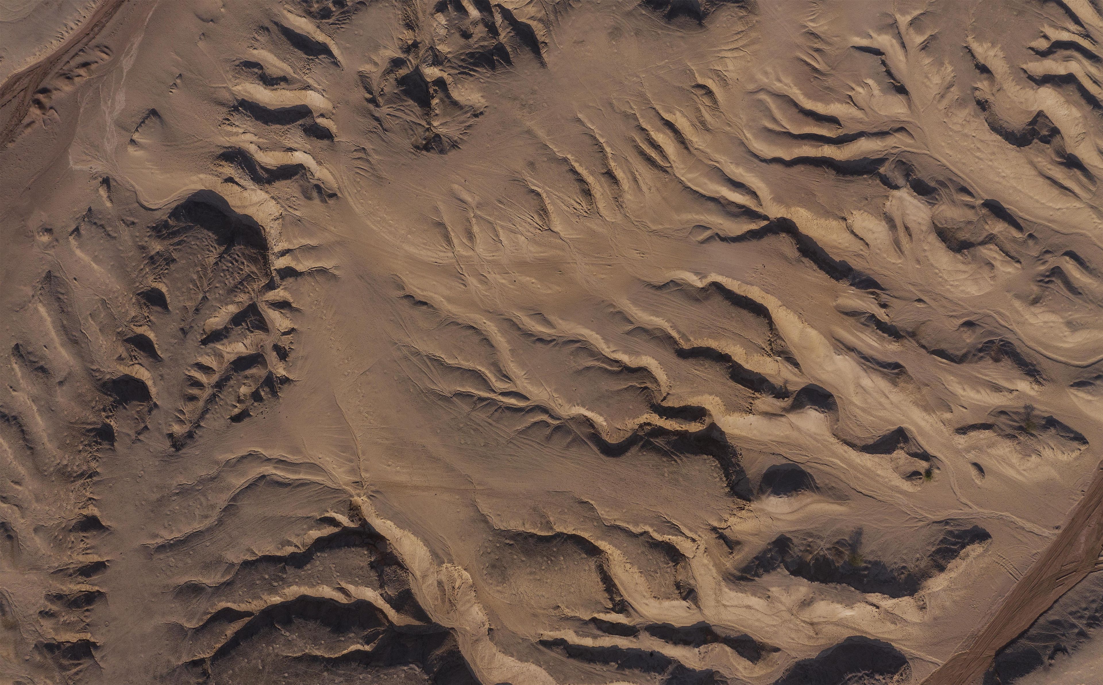 A rugged, barren landscape with undulating terrain and deep valleys.