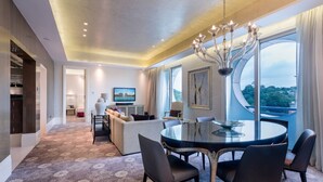 Een moderne hotelkamer met een zithoek, een bank, een kroonluchter en een groot raam met uitzicht.