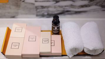 A bathroom vanity with a marble backsplash, a bottle of lotion, and a set of toiletries including a shower cap, shaving kit, and cotton buds.