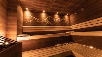 A sauna with wooden walls and benches, a wall-mounted phone, and a ceiling with recessed lighting.