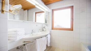 A modern bathroom with a sink, mirror, and window.