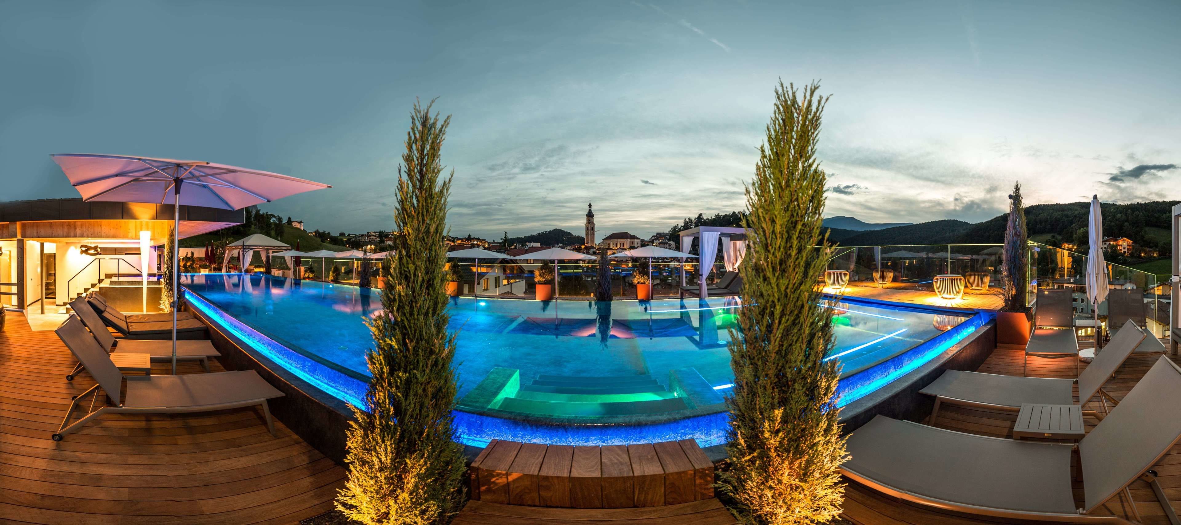 A pool area with lounge chairs, umbrellas, and a view of the surrounding landscape.