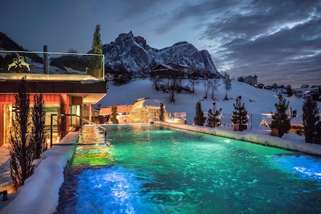 Una piscina techada, una piscina al aire libre, sombrillas