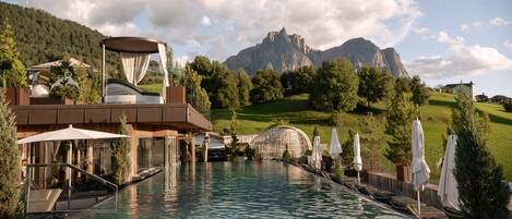 Una piscina techada, una piscina al aire libre, sombrillas