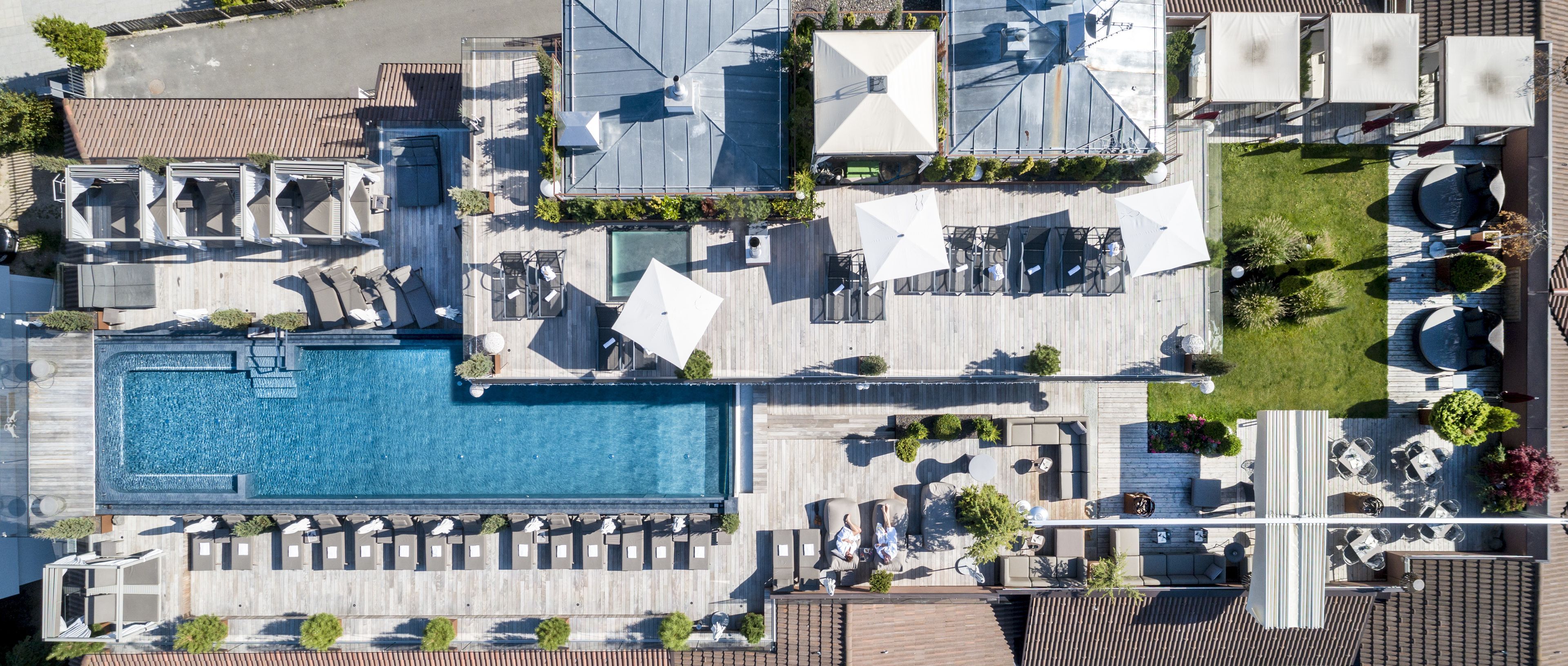 Vista aérea de un resort con una amplia piscina, varias zonas de descanso y mobiliario exterior.