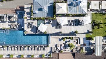 Vista aérea de un resort con una amplia piscina, varias zonas de descanso y mobiliario exterior.