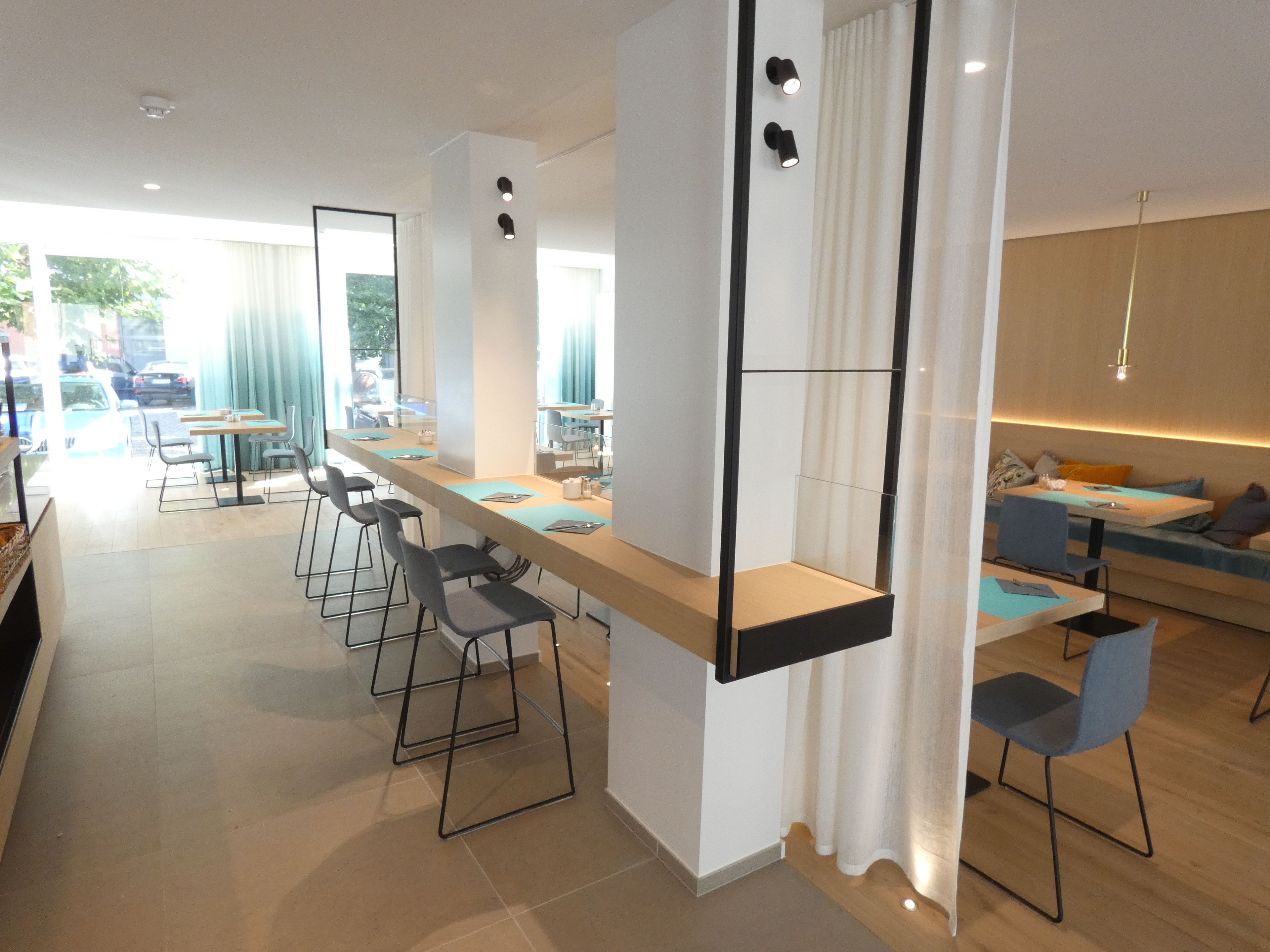 Un comedor moderno con una barra alargada, taburetes y una zona de estar con sofá y sillas.