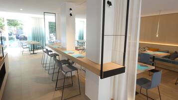 Un comedor moderno con una barra alargada, taburetes y una zona de estar con sofá y sillas.