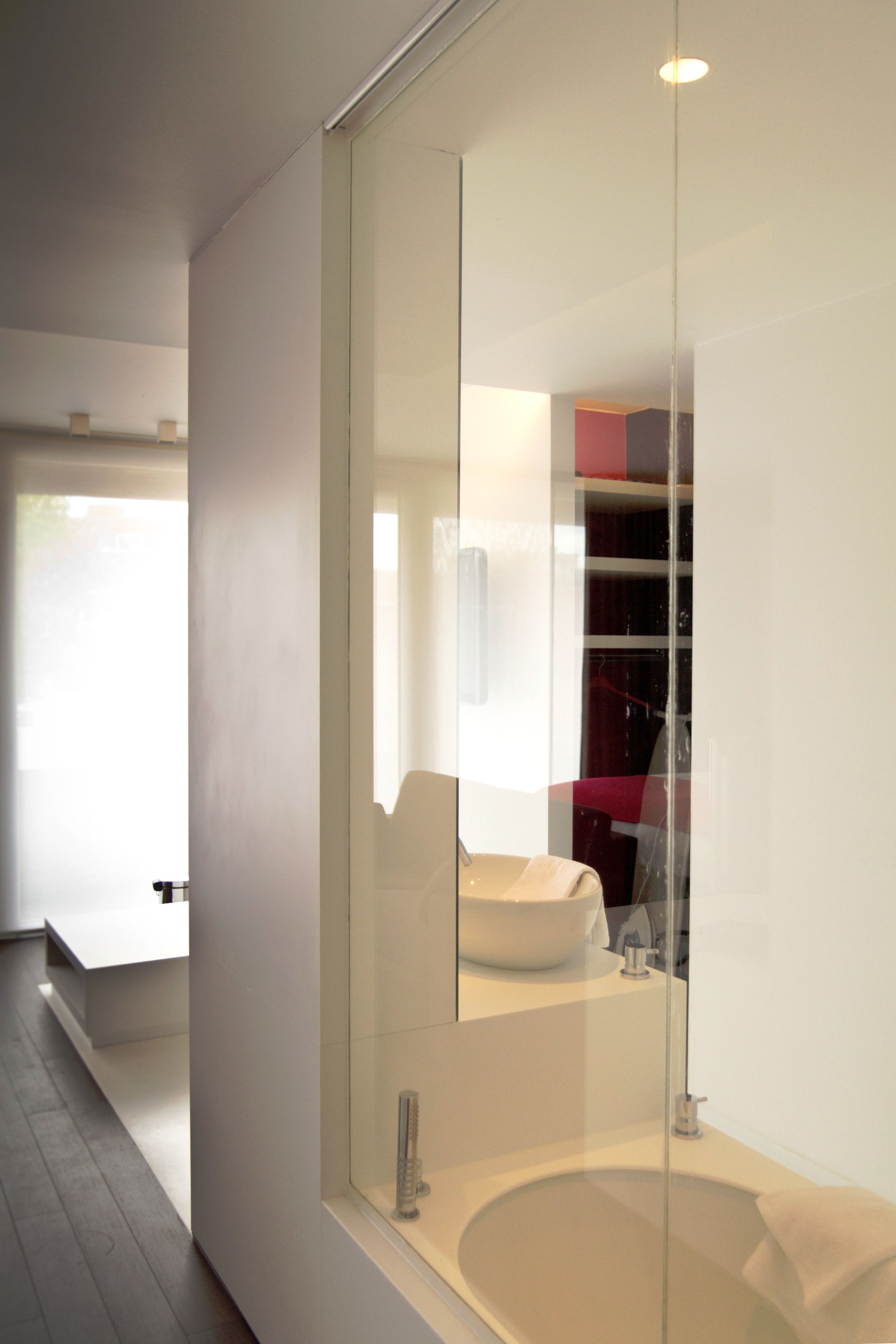 Un baño moderno con una bañera de hidromasaje con mampara de vidrio, un lavabo blanco y un espejo grande.