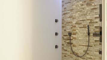 A modern shower with a tiled wall and a handheld showerhead.