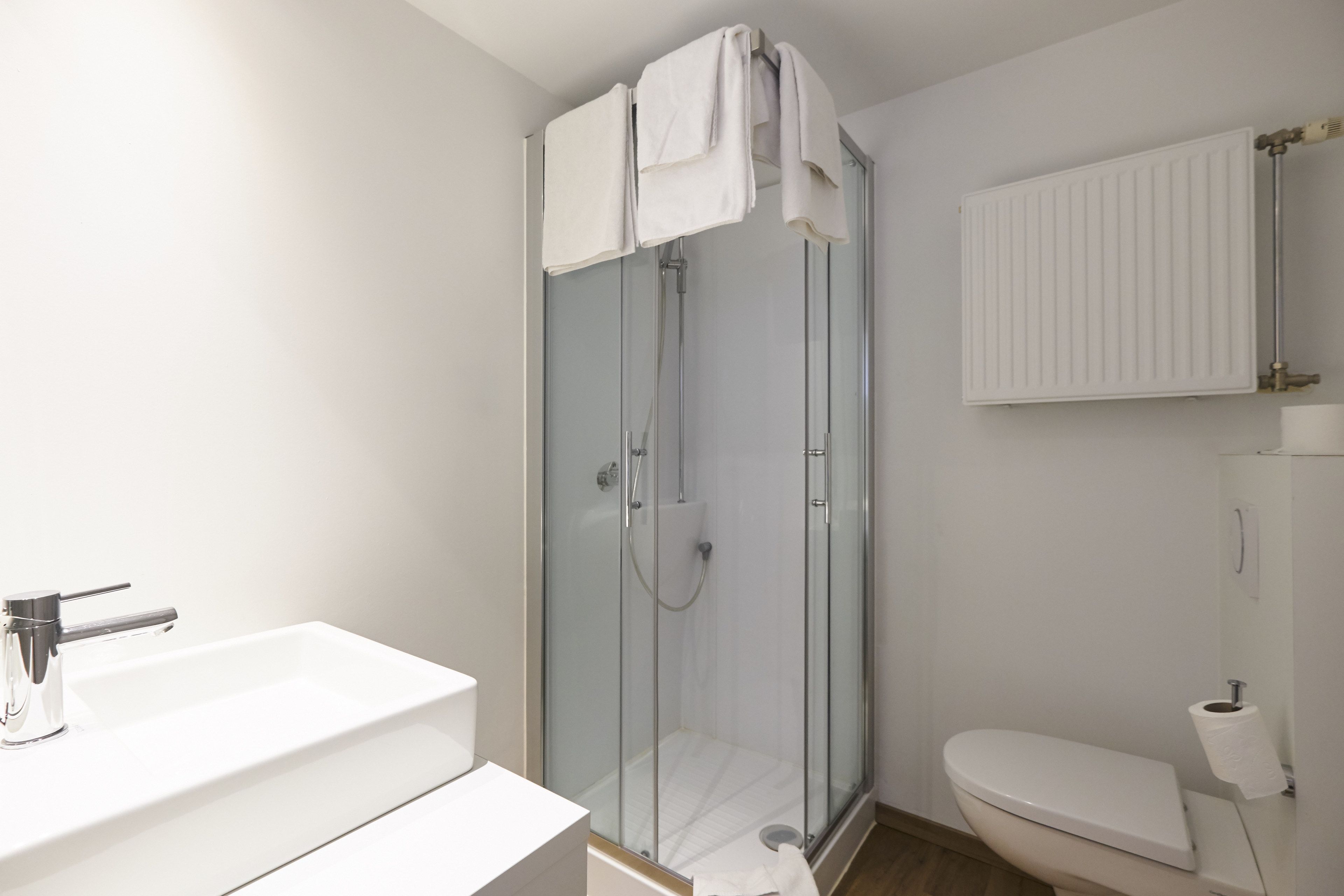 Une salle de bain moderne avec une douche à parois de verre, un lavabo blanc et des toilettes.