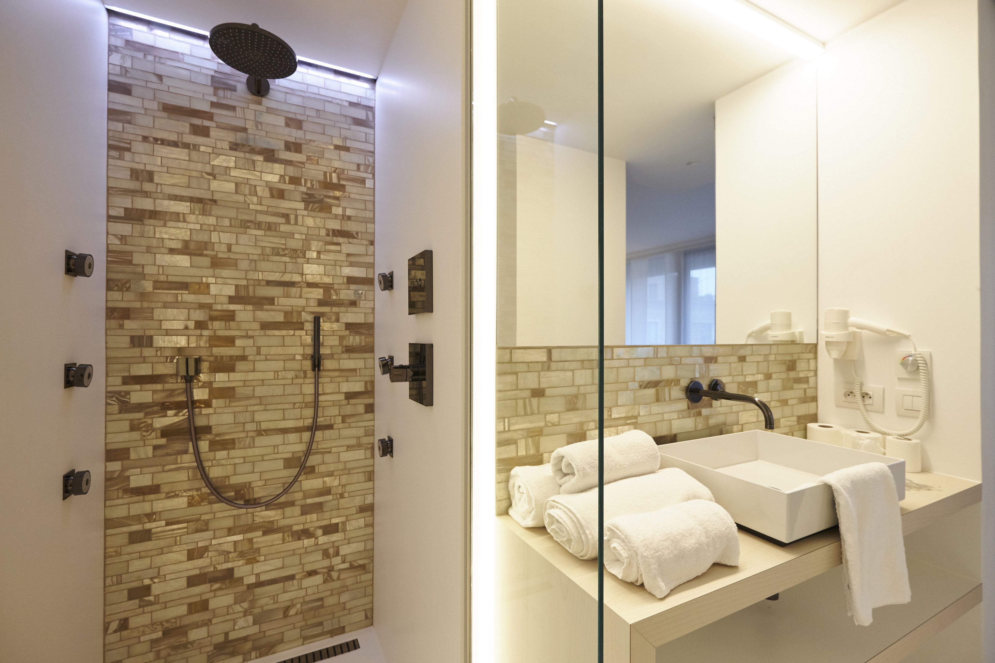 A modern bathroom with a shower, a sink, and a large mirror.