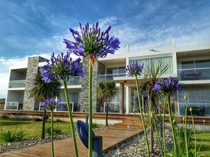 Een modern gebouw met twee verdiepingen, balkons, een stenen gevel en een houten terras.
