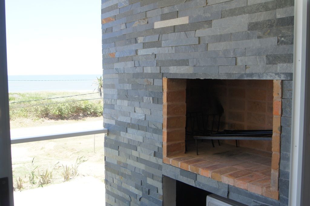 An outdoor stone fireplace with a bench, set against a coastal backdrop.