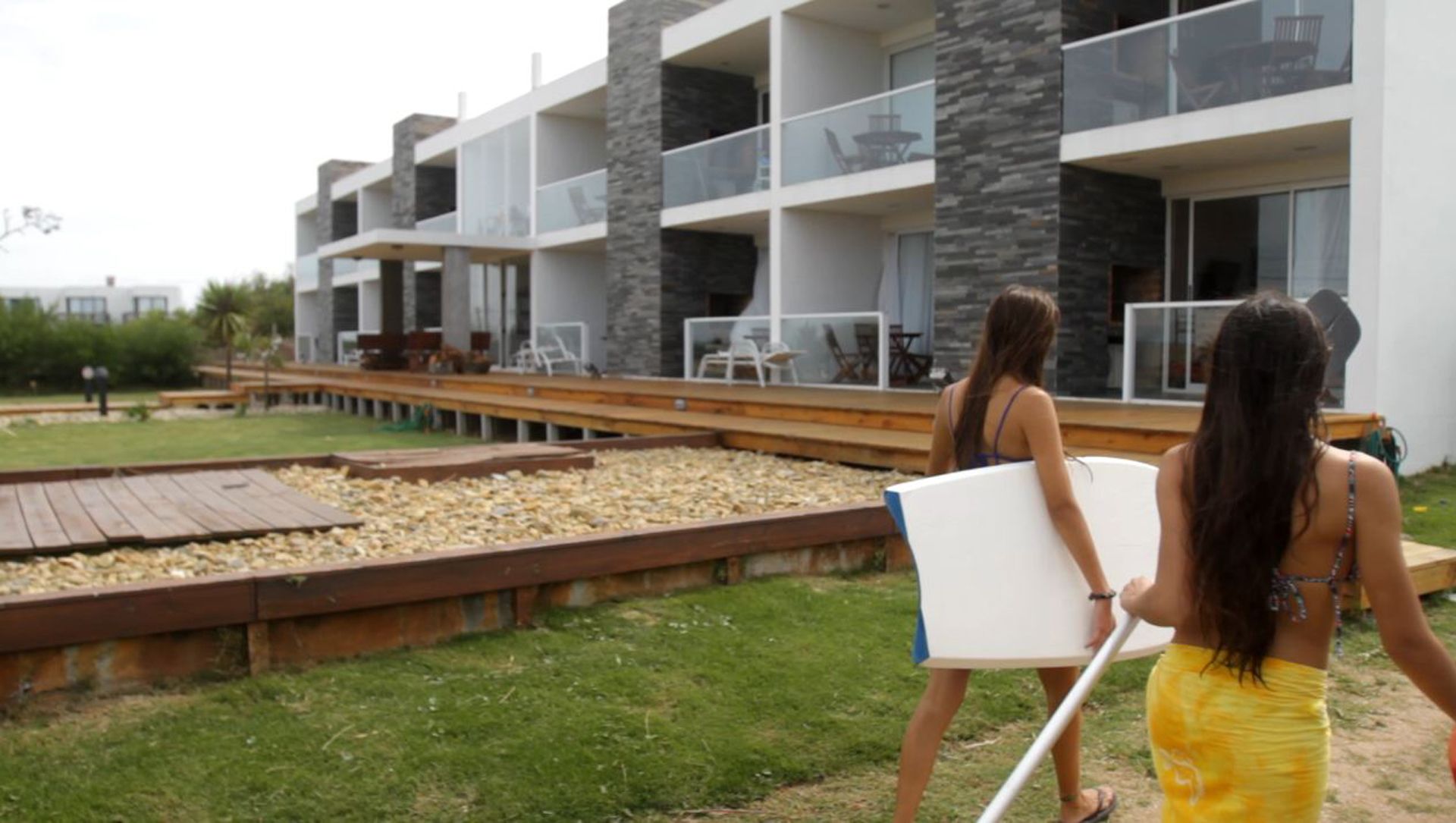 Un immeuble moderne à plusieurs étages, doté de balcons, d’une piscine et d’espaces de détente en plein air.