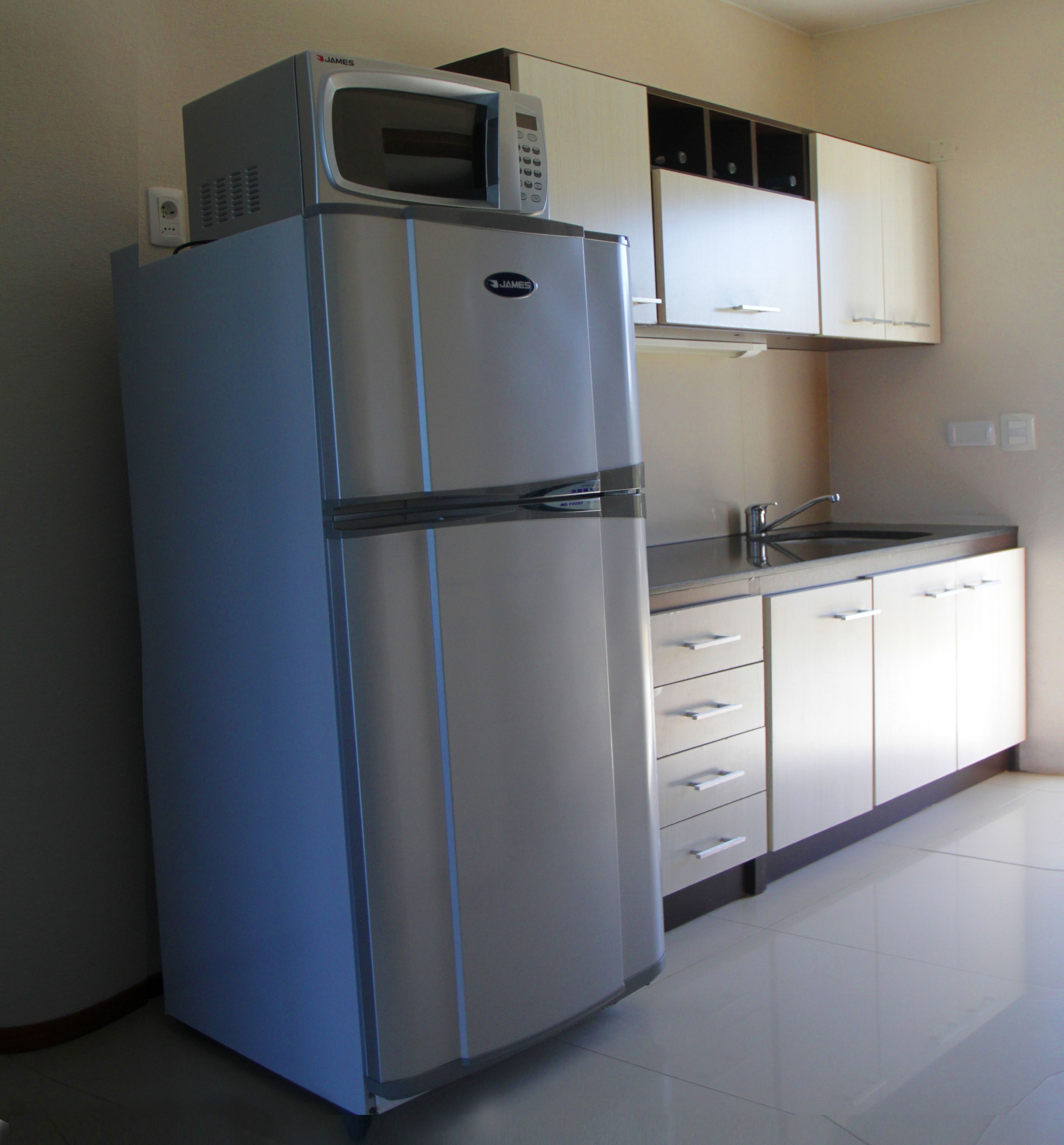 A kitchen with a stainless steel refrigerator, a microwave, and a sink.