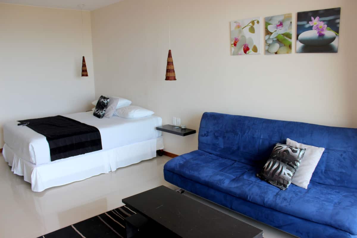 Ein Schlafzimmer mit einem Bett, einem blauen Sofa und einem kleinen Tisch.