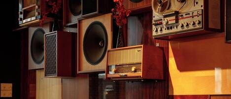 A restaurant interior with wooden paneling, multiple speakers, and a vintage radio. Tables and booths are available for seating.
