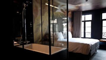 Ein modernes Schlafzimmer mit einer gläsernen Dusche, einem großen Bett und Balkonblick.
