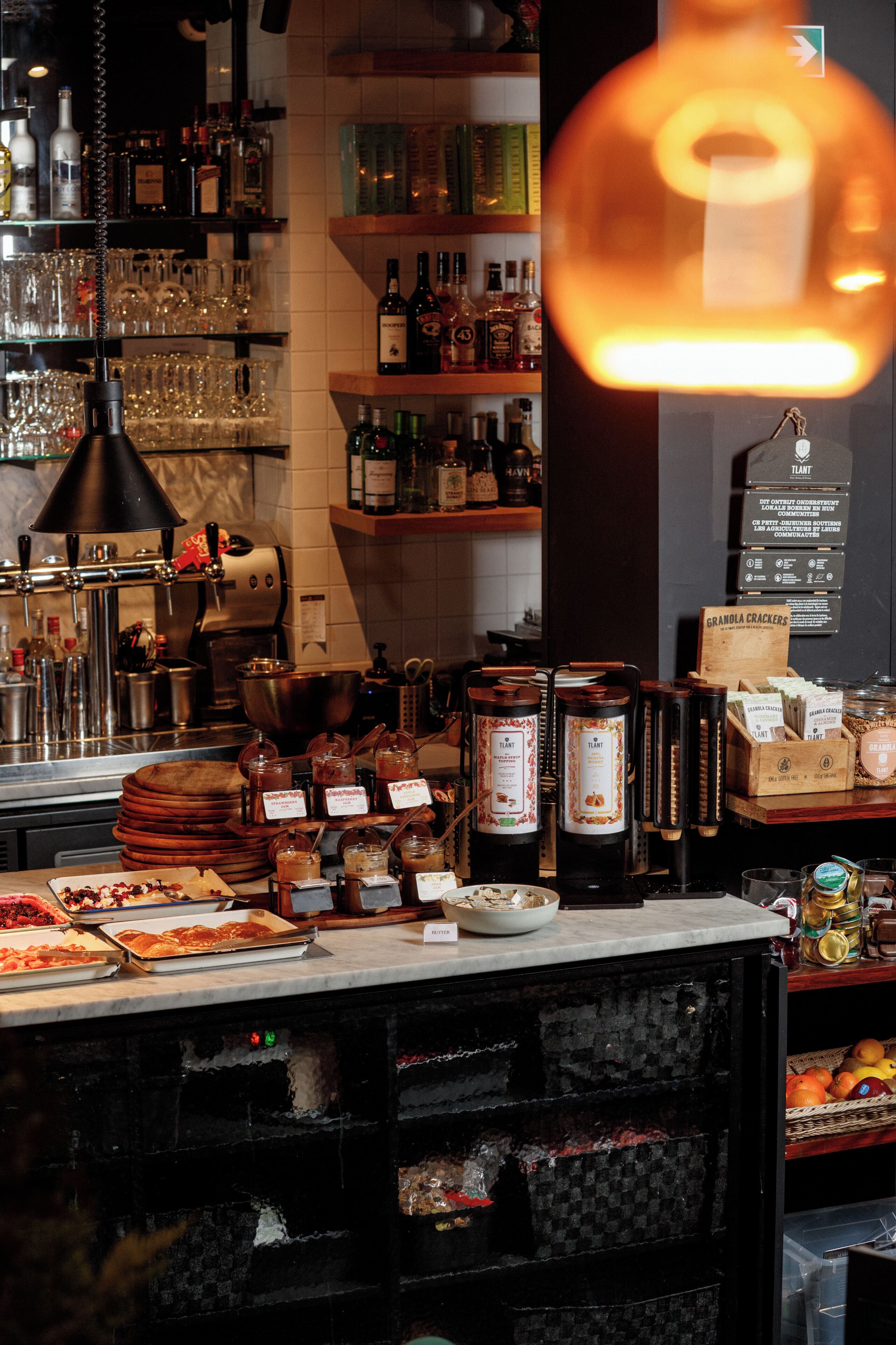 Un espace bar avec des étagères remplies de bouteilles, de verres et une machine à café.