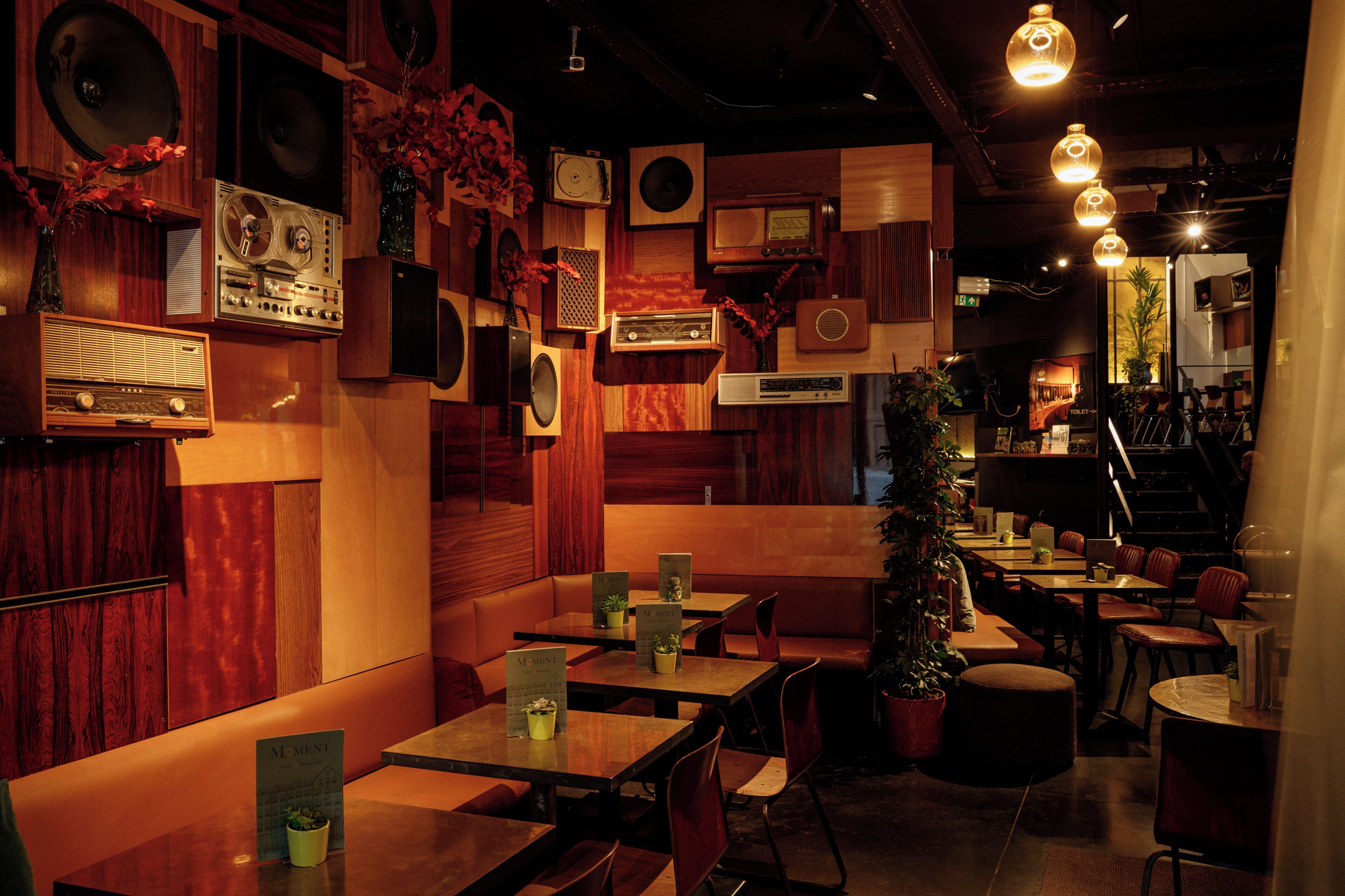 Interior de restaurante con paneles de madera, equipo de audio antiguo y varias zonas de estar.