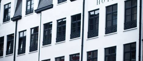A white building with the word "HOTEL" on the facade, multiple windows, and a year "2012" on the top right.