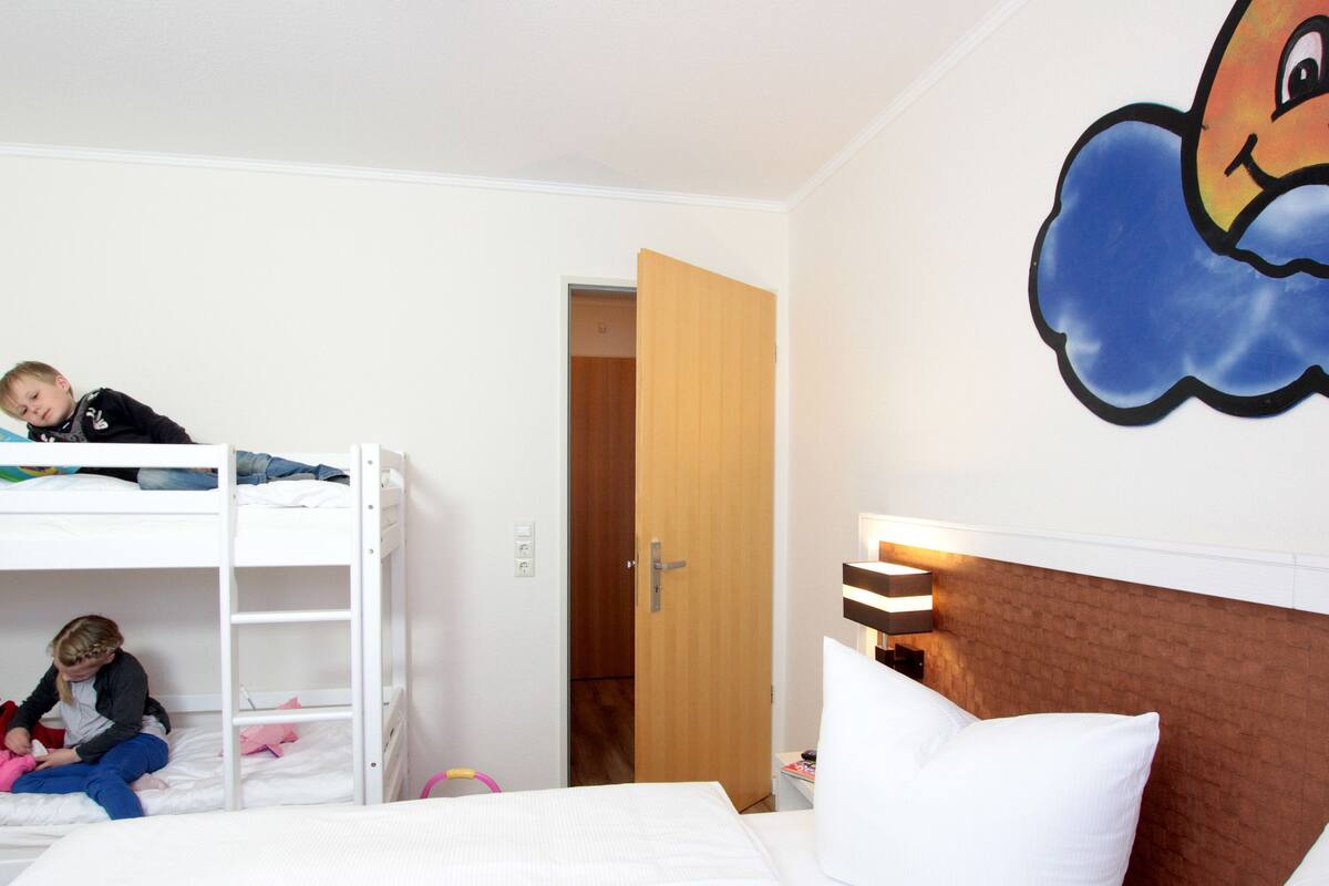 A hotel room with bunk beds, a wooden door, and a wall mural.