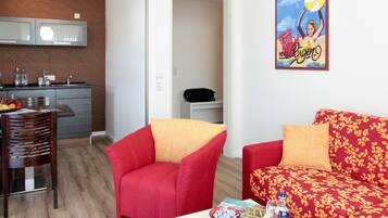 A compact living space with a dining area, a kitchenette, and a red sofa with floral upholstery.
