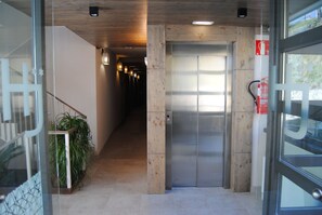 A hallway with a wooden floor, a glass door, and a fire extinguisher on the wall. - Hotel Santa Bàrbara (Cercs)