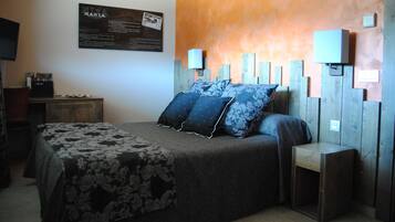 Un dormitorio con cama, escritorio, silla, televisor y una lámpara fijada a la pared.