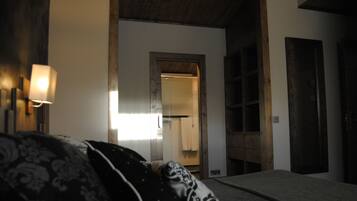 Una habitación con cama, lámpara, armario y un espejo que refleja un baño.