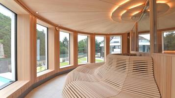 Un intérieur moderne avec de grandes fenêtres, un banc en bois aux lignes courbes et un plafond réfléchissant.