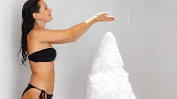 Una persona con traje de baño negro de pie junto a un objeto blanco grande.