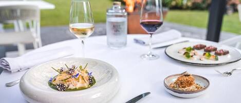 A table set with plates of food, glasses of wine, and a water bottle.