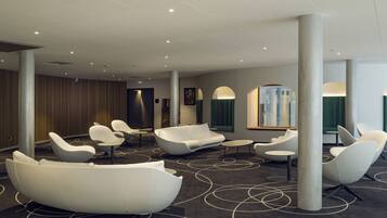 A modern lounge area with white, curved seating and a patterned carpet.