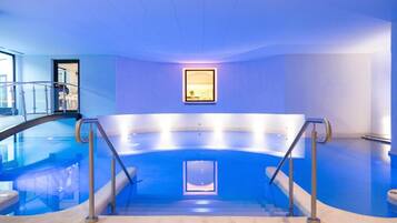 An indoor swimming pool with a glass wall, metal railings, and a framed picture on the wall.