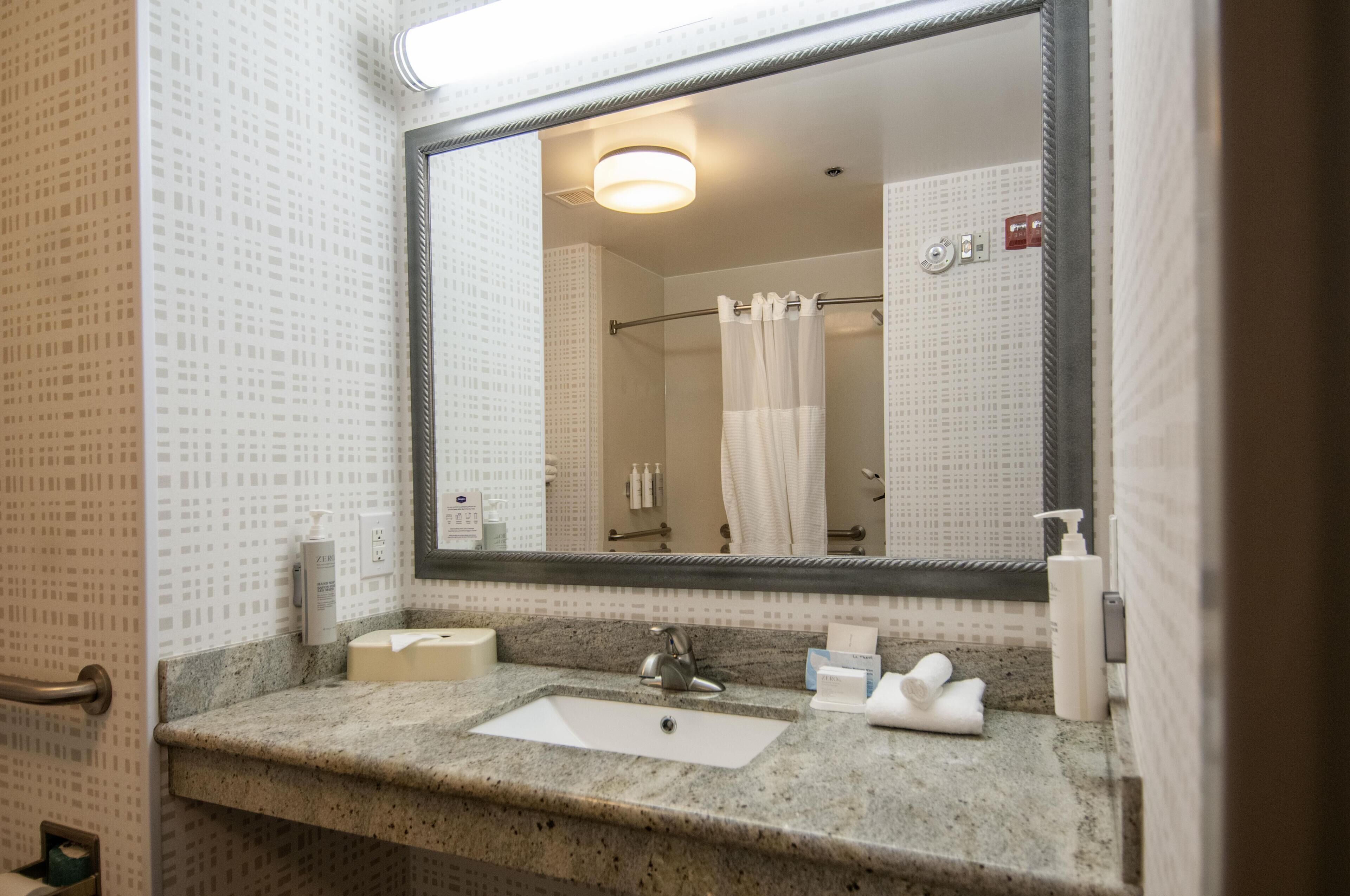 Une salle de bain avec un lavabo, un miroir et un rideau de douche.