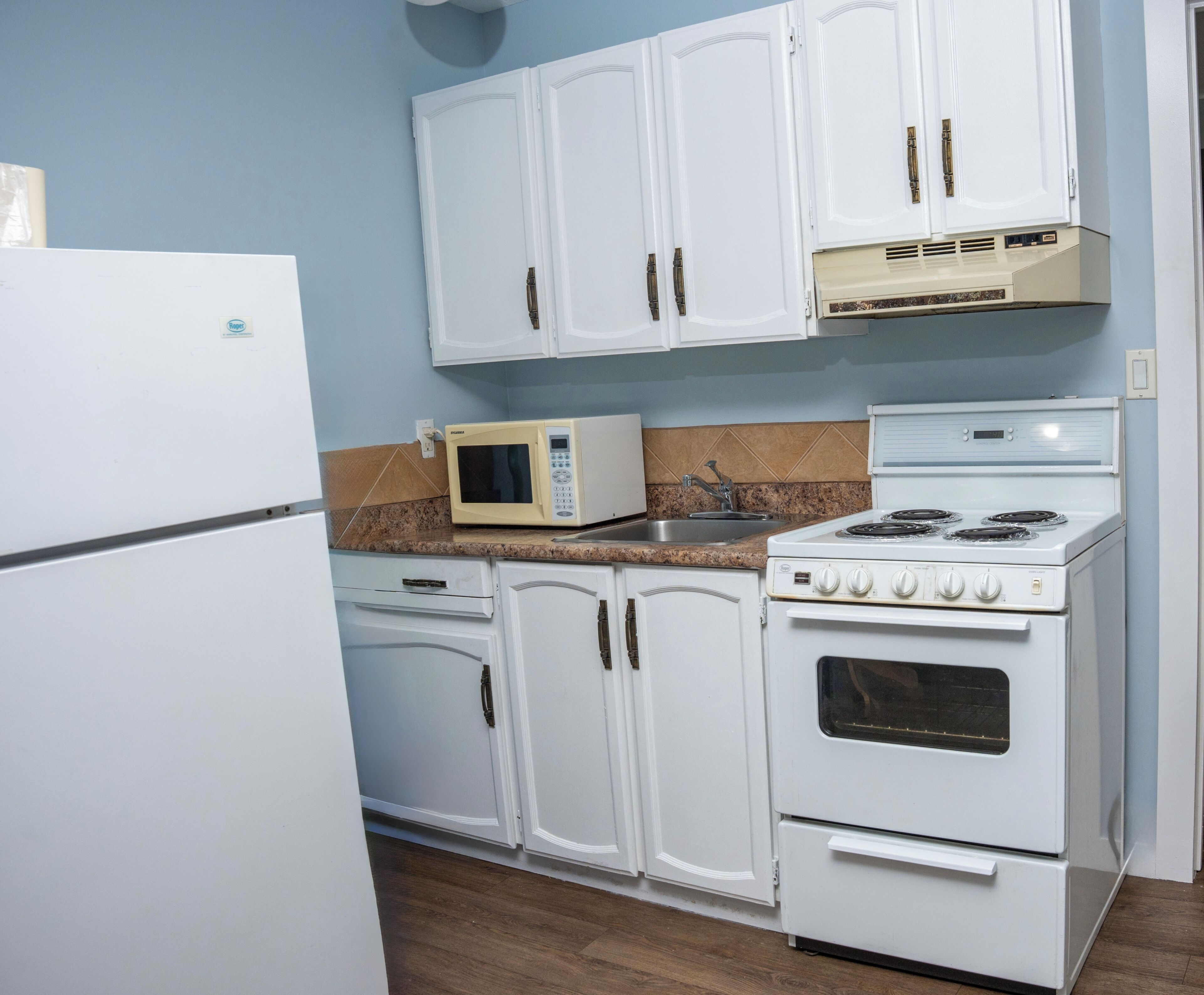A kitchen with white cabinets, a microwave, a stove, and a refrigerator.