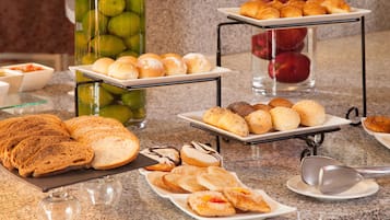 Un buffet proposant une variété de pains, de viennoiseries et de fruits.