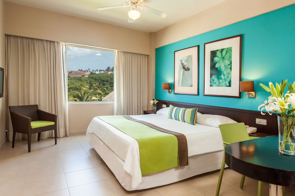 Une chambre d’hôtel avec un grand lit, un bureau, une chaise et une vue sur l’extérieur.