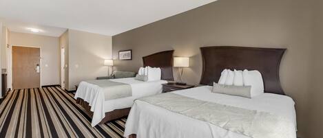 A hotel room with two beds, a striped carpet, and a door leading to another room.